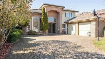 A two-story house with a brick facade, a garage, and a paved driveway.