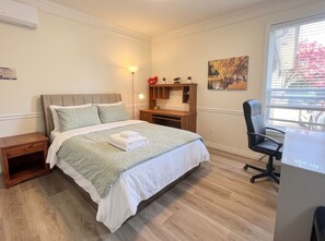 A bedroom with a bed, bedside table, desk, chair, and a window with blinds. - Two Bedrooms/4 Guests 15 Min YVR, A/C (Richmond)