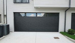 A modern garage with a dark door, a small window, and a concrete driveway. - East Nashville Wellness Stay: Sauna | Gym| Rooftop (Nashville)