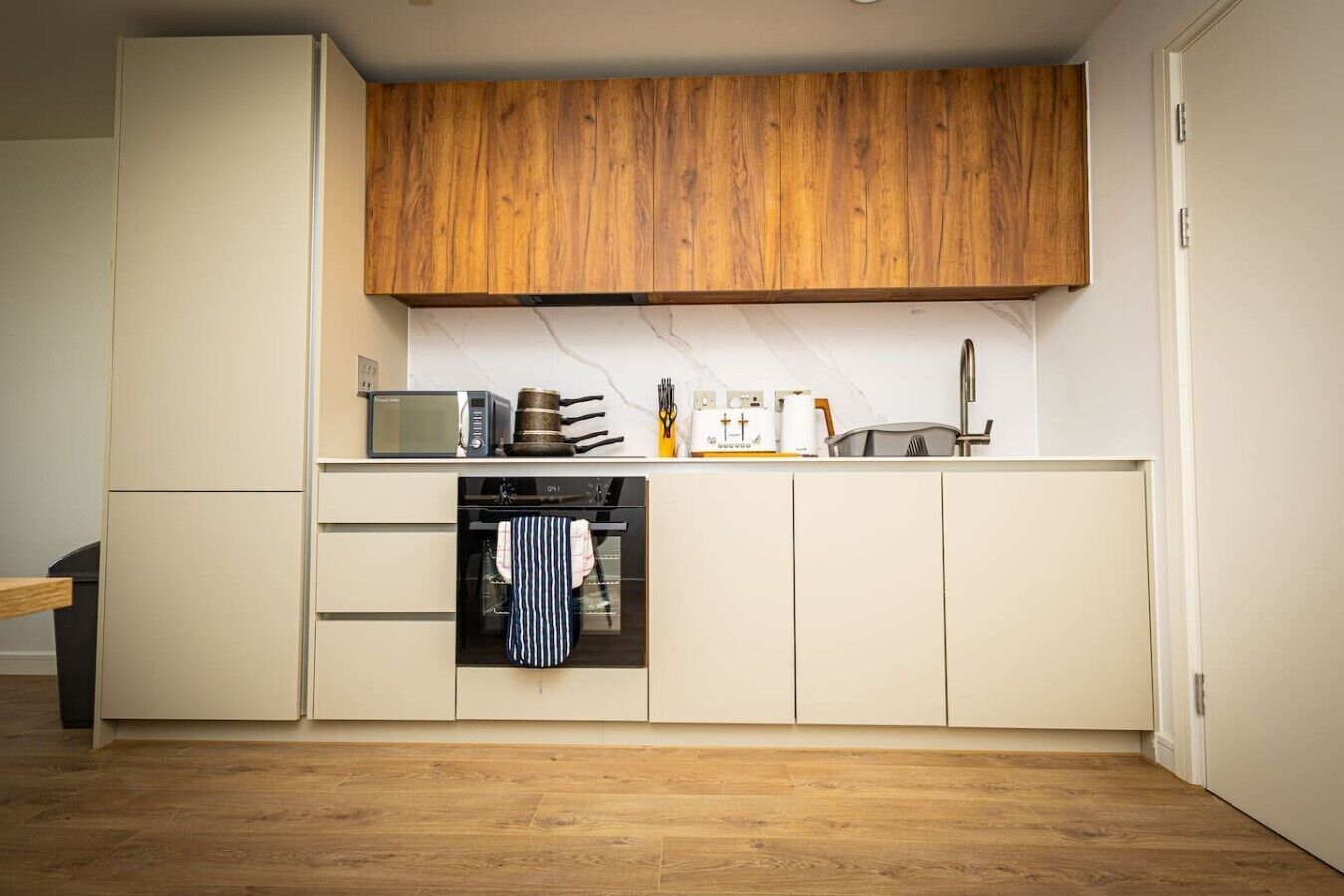 A compact kitchen with wooden cabinets, a microwave, a stove, and a small oven.