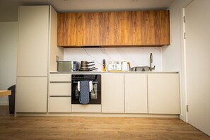 A compact kitchen with wooden cabinets, a microwave, a stove, and a small oven. - Birmingham City Retreat No 146 (Birmingham)
