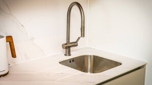 Eine Küche mit einer Edelstahl-Spüle, einer Tasse mit Holzgriff und einer Marmor-Spritzschutzwand.