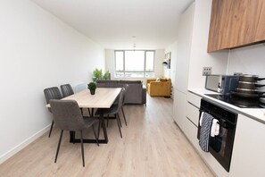 A modern kitchen with a dining area, a sofa, and a view through the window. - Birmingham City Retreat No 146 (Birmingham)