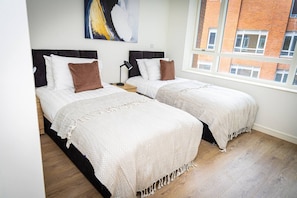 A bedroom with two beds, a large window, and a view of a brick building. - Birmingham City Retreat No 146 (Birmingham)