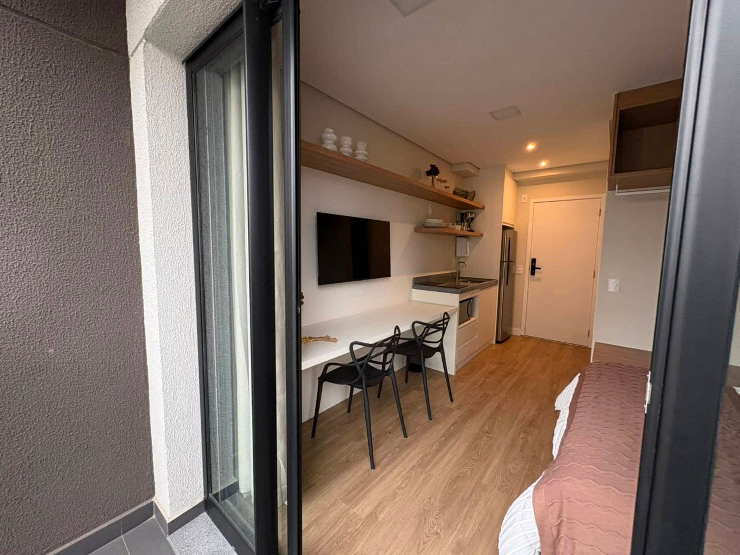 Un espace de vie compact comprenant un coin cuisine, un espace repas et un lit.