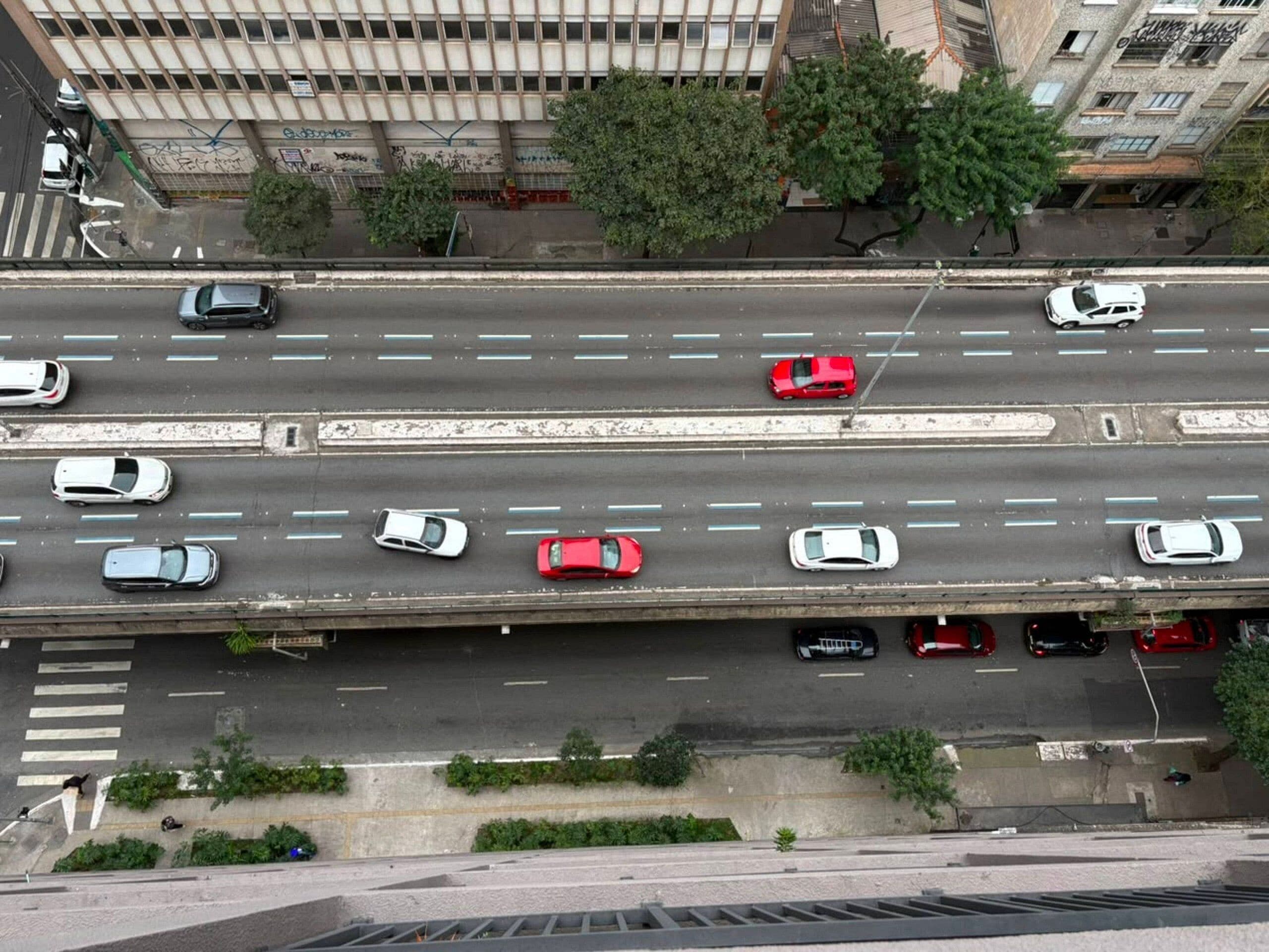 A multi-lane highway with vehicles, a pedestrian crossing, and buildings in the background.
