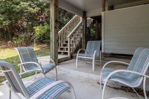 Eine überdachte Veranda mit vier gestreiften Stühlen und einer Holztreppe.