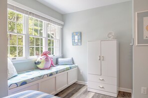 Ein Zimmer mit Fensterbank, einem weißen Kleiderschrank und einem an der Wand befestigten Globus.