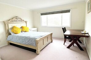 Una camera da letto con un letto, un comodino, una sedia e una finestra.