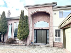 Ein zweistöckiges Haus mit Ziegelaußenwand, einer grünen Tür und der Hausnummer 8751 über dem Eingang.