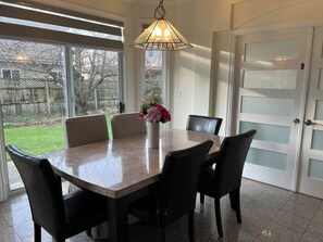 Ein Essbereich mit Tisch und Stühlen, einer Vase mit Blumen und einer Tür mit Milchglasfenstern.