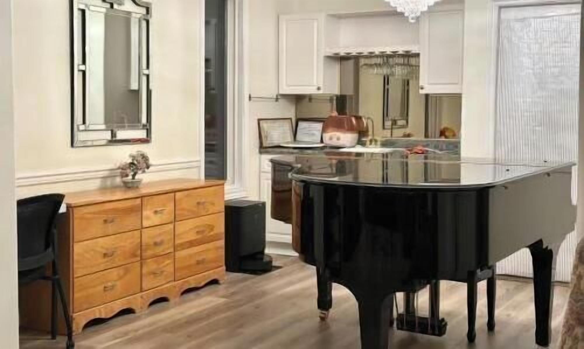 Une pièce comprenant une table de billard, une commode en bois et un coin repas agrémenté d ’un lustre.