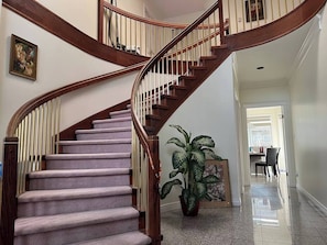 A spiral staircase with wooden railings and carpeted steps leading to a dining area. - Two bedroom suite in a House/ 15 min YVR, AC (Richmond)