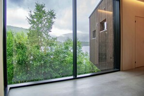 A room with a large window overlooking a forest and a body of water. - Architect-designed cabin with fjord views (Bryggja)