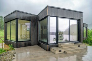 A modern two-story building with large glass windows and a wooden deck.