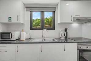 A modern kitchen with a built-in microwave, toaster, sink, and kettle. - Casa Da Costa: Sea View, Private Terrace & Wi-Fi in São Vicente, Madeira (Sao Vicente)