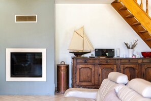 Ein Wohnzimmer mit Kamin, einem Segelbootsmodell, einem Fernseher und einer Holztreppe.