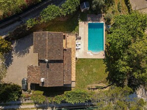 Eine Luftaufnahme eines Anwesens mit Swimmingpool, überdachter Terrasse und umgebender Bepflanzung.