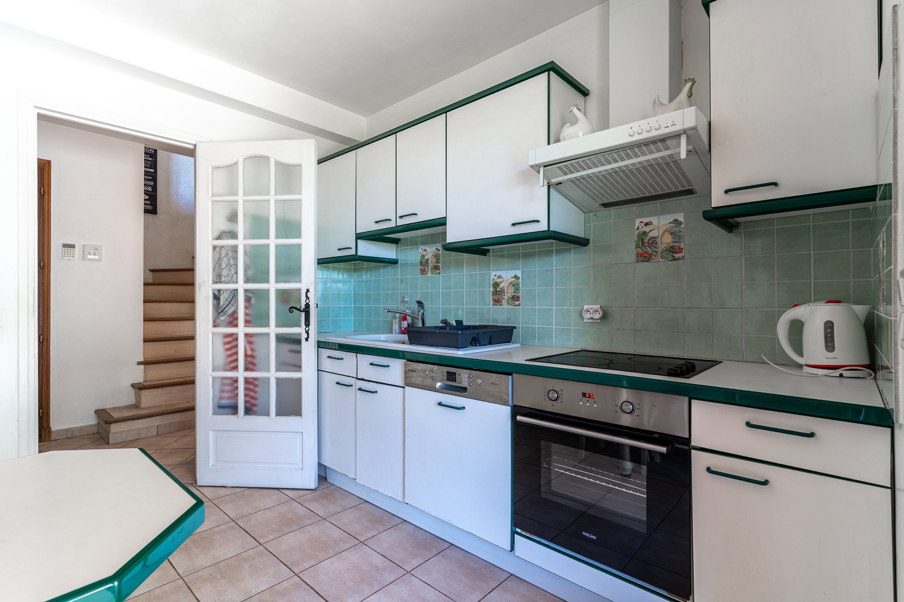 A compact kitchen with white cabinets, a built-in oven, and a gas stove.