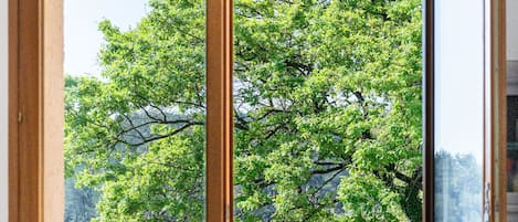 A room with a large sliding glass door leading to a poolside area with a view of a tree and a body of water.
