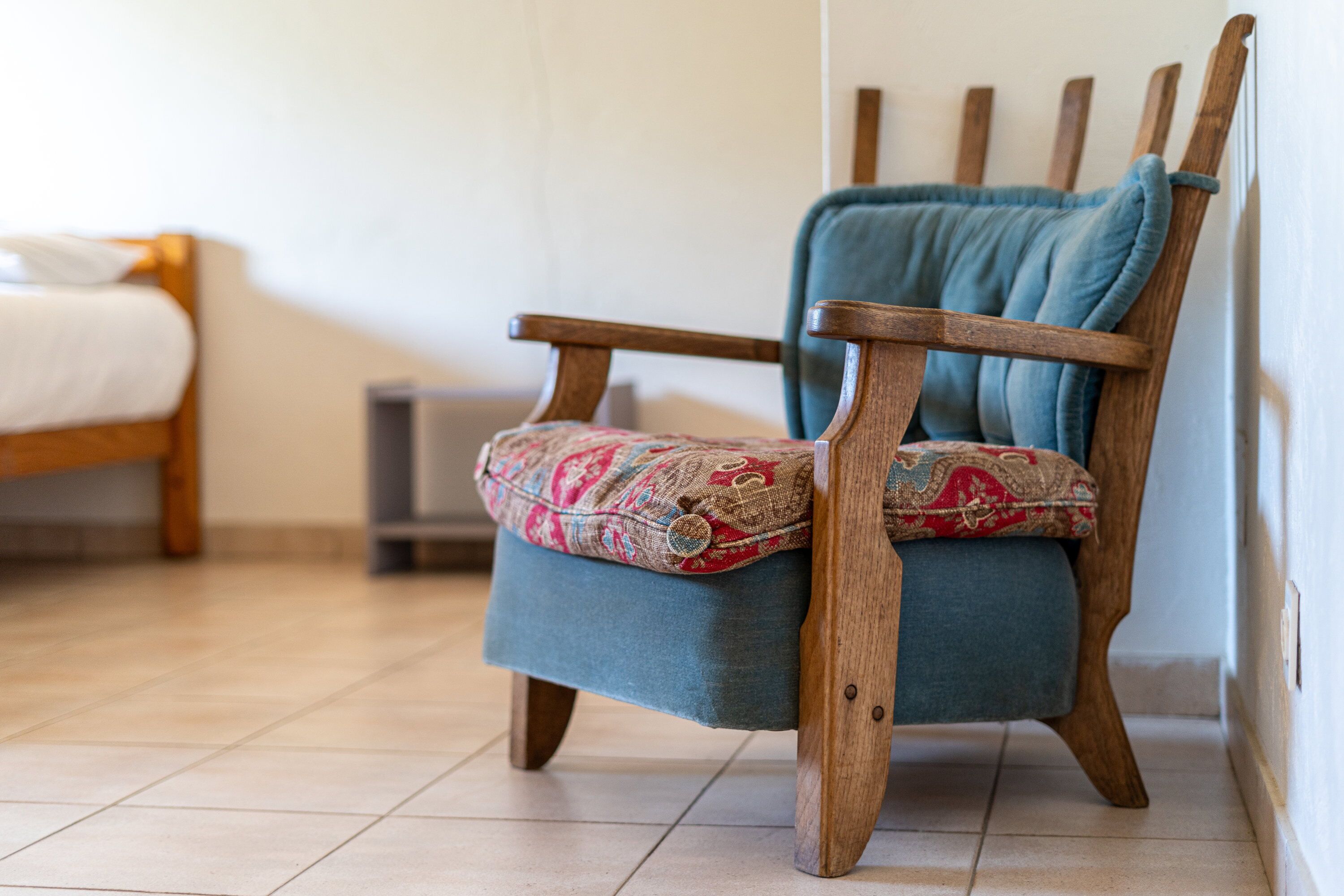 A wooden chair with a patterned cushion and a blue throw blanket.