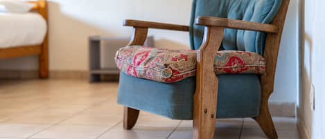A wooden chair with a patterned cushion and a blue throw blanket.