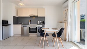 A modern kitchen with a dining area, featuring a built-in oven, microwave, and dishwasher. - Escale Calistea : tout confort avec piscine & clim (Roquefort-les-Pins)
