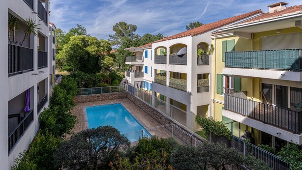 A multi-story building with a central swimming pool surrounded by balconies and greenery. - Escale Calistea : tout confort avec piscine & clim (Roquefort-les-Pins)