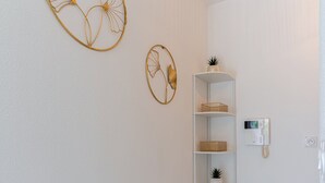 A clean, modern hallway with a white wall, a white shelf unit, and two decorative wall art pieces. - Escale Calistea : tout confort avec piscine & clim (Roquefort-les-Pins)