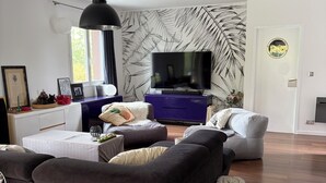 Un salon moderne comprenant un ensemble de canapés, un téléviseur et un mur décoratif.