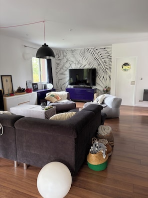 Ein modernes Wohnzimmer mit einer Sofagarnitur, einem Fernseher und einer Wandverzierung.