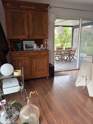 A room with a wooden cabinet, a printer, a lamp, and a view of an outdoor patio with chairs. - A cozy villa and spa between the ocean and the Basque Country... Le Clos des Chats Heureux (Saint-Martin-de-Seignanx)
