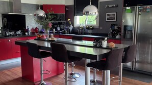 Une cuisine moderne dotée d’un îlot central, de tabourets de bar, d’appareils électroménagers en acier inoxydable et d’une grande fenêtre.