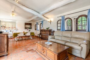 A spacious living room with a leather sofa, a wooden coffee table, and a dining area with a table and chairs. - L'Absolu Azur : Bulle de Calme & Piscine (Grasse)