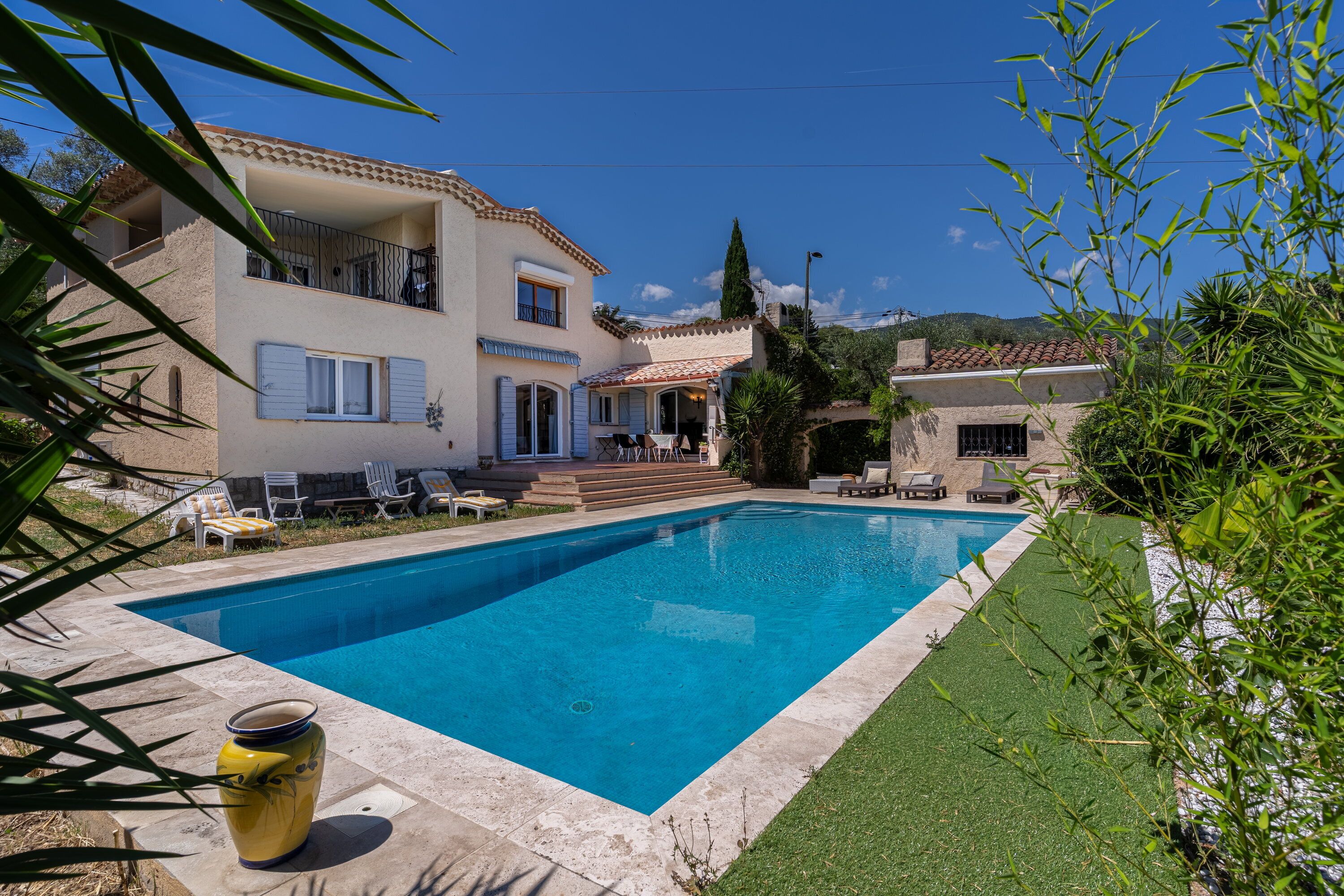 A two-story building with a swimming pool, outdoor seating, and a view of the surrounding landscape.