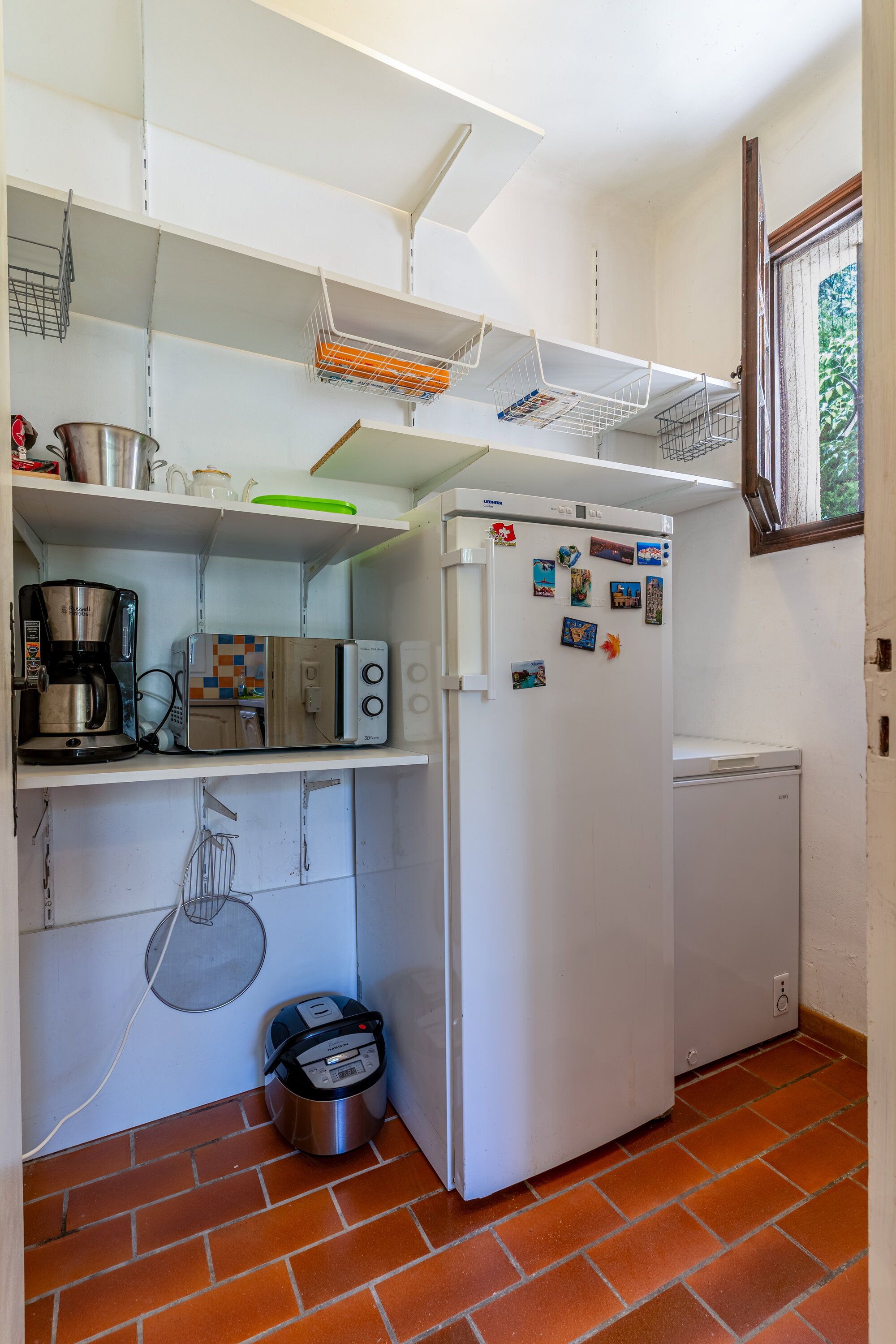 A compact kitchen with a white refrigerator, a coffee maker, a microwave, and a toaster.