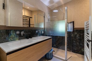 Une salle de bain moderne avec un grand miroir, deux lavabos, une douche et des toilettes.