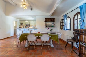 A dining area with a table set for two, white chairs, a green tablecloth, and a ceiling fan. - L'Absolu Azur : Douceur de vivre & piscine (Grasse)