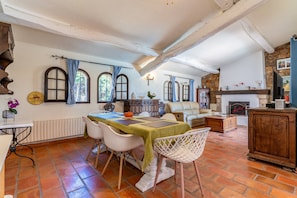 A dining area with a table set for four, a fireplace, and a stone wall. - L'Absolu Azur : Bulle de Calme & Piscine (Grasse)