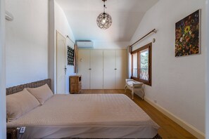 Ein Schlafzimmer mit einem Bett, einer Kommode, einem Fenster und einem Bild an der Wand.