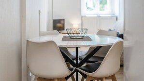 Et moderne spiseområde med et rundt bord, fire stole og en geometrisk skål som midtpunkt.