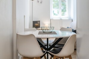 Ein moderner Essbereich mit einem runden Tisch, vier Stühlen und einer geometrischen Drahtschale als Mittelpunkt.
