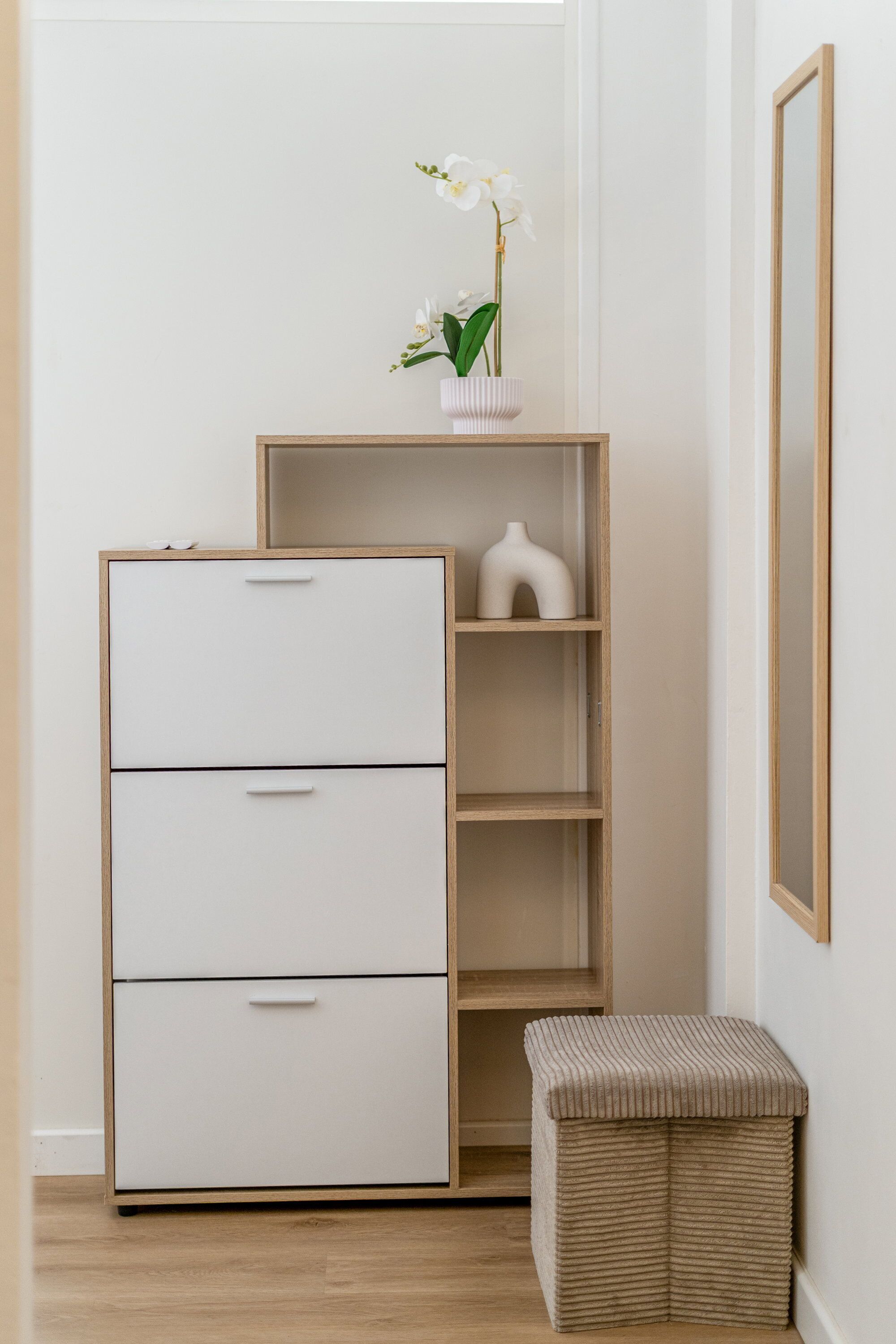 Une pièce au décor minimaliste, avec un classeur blanc, une bibliothèque en bois et un banc en osier.