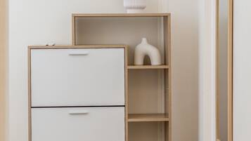 Une pièce au décor minimaliste, avec un classeur blanc, une bibliothèque en bois et un banc en osier.