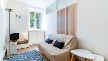 Una sala de estar moderna con un sofá, una mesita, un televisor y un tapete estampado.