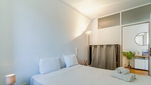 Et hotelværelse med seng, natbord, lampe og et spejl.