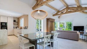 A modern kitchen with a dining area, a built-in oven, and a large window. - La Villa Estérelle — Vue golf, piscine & élégance (Saint Raphael)
