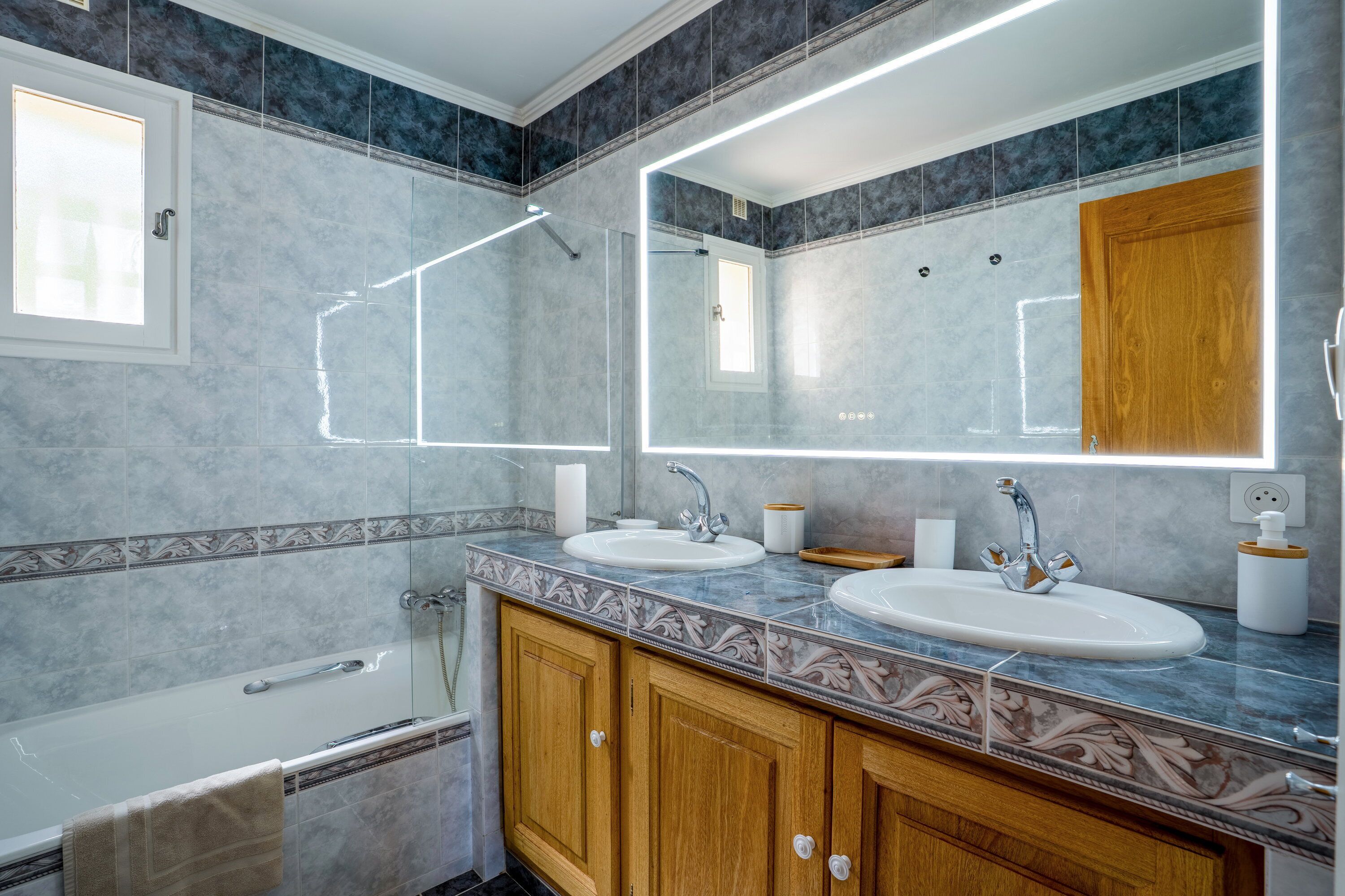 A modern bathroom with two sinks, a large mirror, and a shower enclosure.