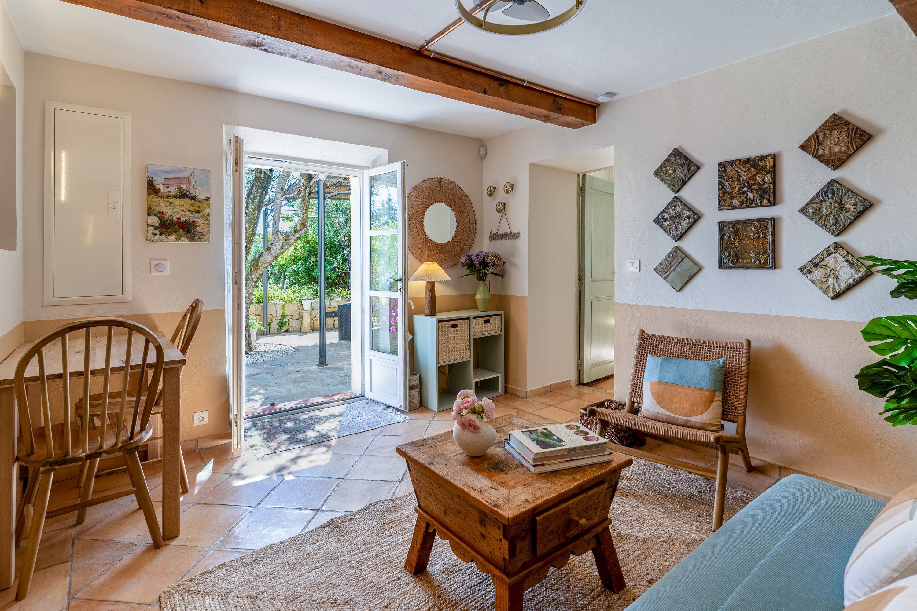 A room with a wooden chair, a table with books, a sofa, and a wall with decorative items.