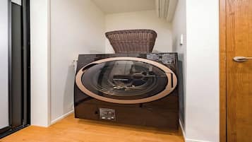 A compact, modern laundry room with a built-in washer and dryer, a wicker basket on top of the dryer, and a wooden floor.